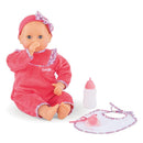 Corolle Mon Grand Poupon Purple Chérie doll in a pink outfit, sucking her thumb, with a bottle and bib beside her.