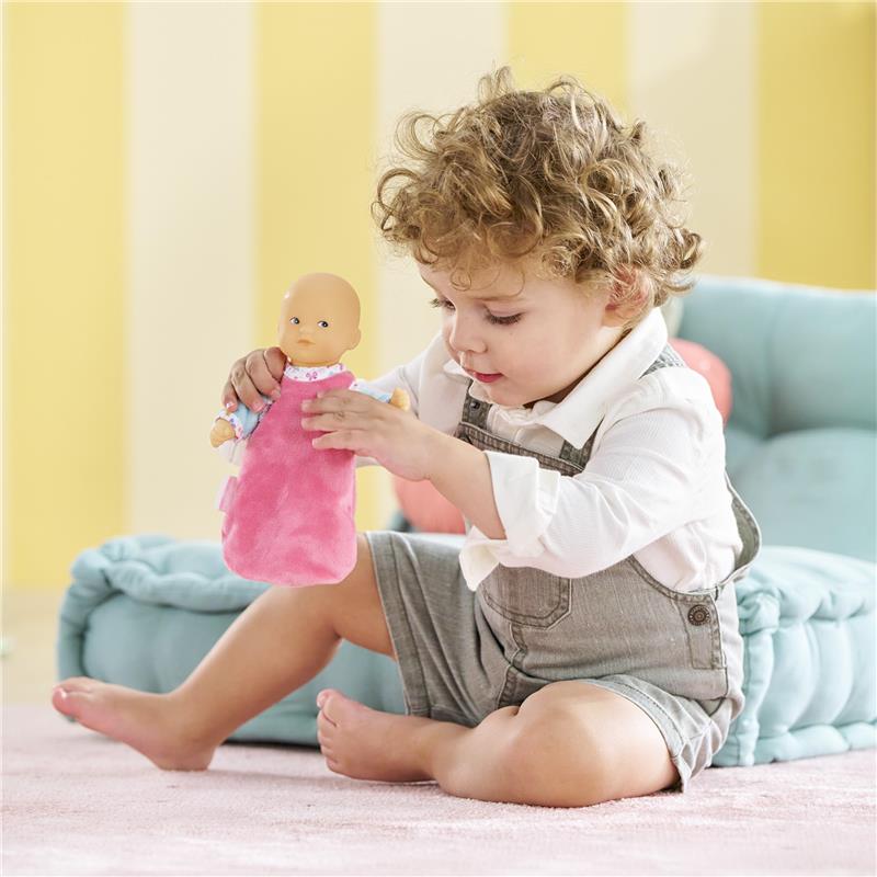 Child playing with the Corolle My First Doll, Mini Hug Bonne Nuit, dressed in a pink outfit, in a cozy room setting.