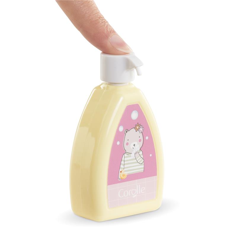 Yellow bottle of Corolle doll accessory lotion with a bear illustration, being squeezed by a finger.