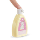Yellow bottle of Corolle doll accessory lotion with a bear illustration, being squeezed by a finger.