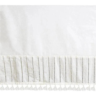 White crib bed skirt with decorative woven trim and tassels along the bottom edge.