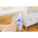 Cordless Crane inhaler held in hand, featuring a facial mask and a power button, used for warm and cool mist therapy.