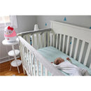 Hello Kitty ultrasonic humidifier on a bedside table next to a crib with a sleeping baby in a softly decorated nursery.