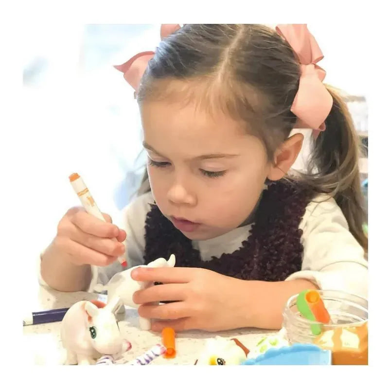 Child coloring a white Scribble Scrubbie animal toy with markers, showcasing creativity and hands-on play.