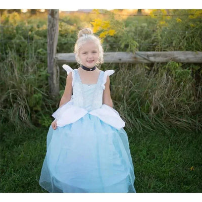 A young girl wears a Deluxe Disney Cinderella dress featuring a light blue satin bodice, white puff sleeves, and a flowing skirt, smiling outdoors.