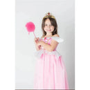 A young girl smiles while wearing a pink Disney princess dress, a sparkling crown, and holding a pink wand with a pom-pom.