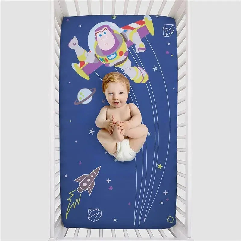 Crown Crafts Disney Buzz Lightyear crib fitted sheet featuring Buzz Lightyear and outer space graphics with a baby in a crib.
