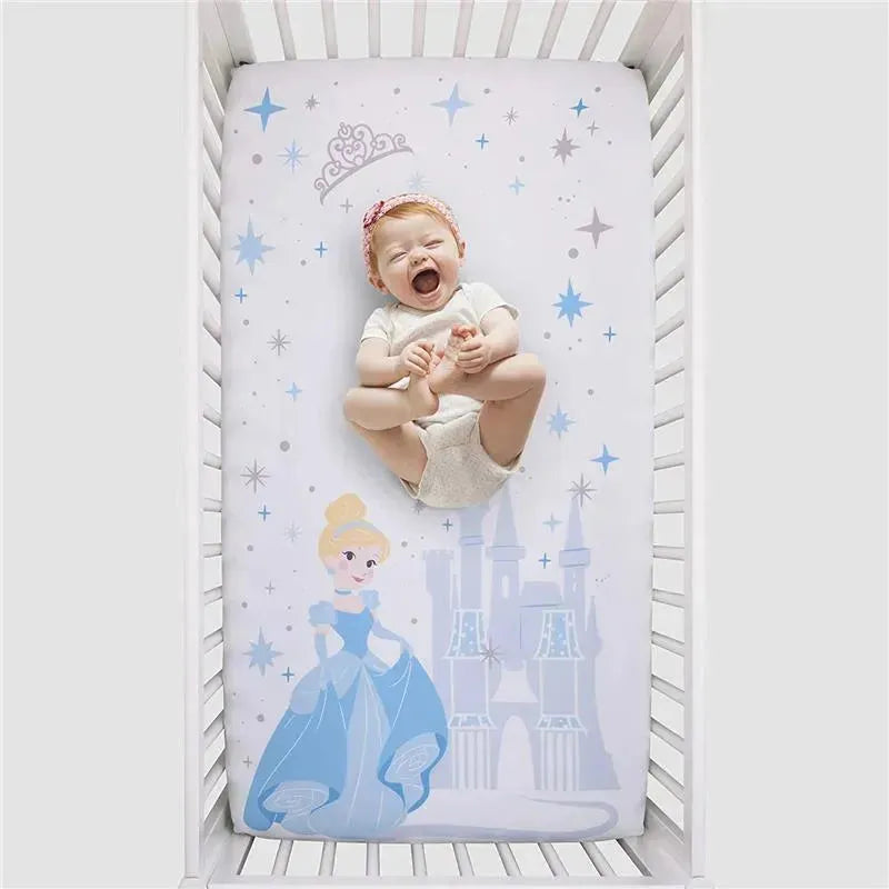 Crown Crafts Disney Cinderella crib fitted sheet featuring Cinderella and a castle, with a smiling baby playing on it.