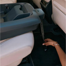 Installation of the Cybex Aton G2 infant car seat load leg base in a vehicle, with a hand adjusting the leg support.