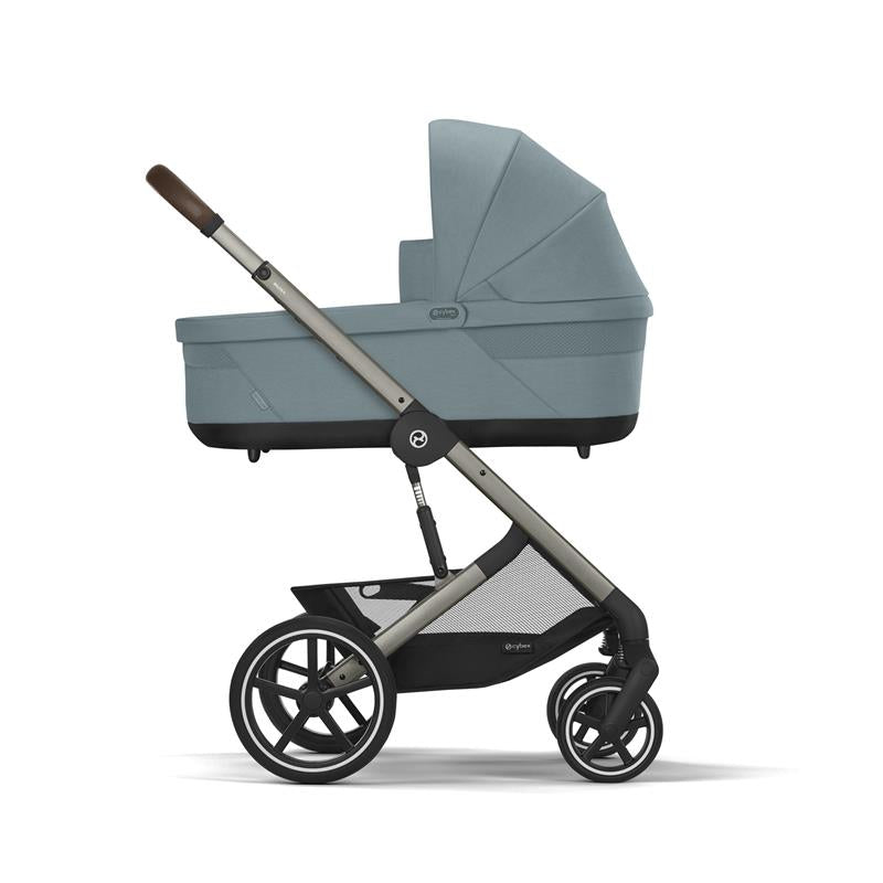 Cybex Balios Cot S Lux in Stone Grey, featuring a sleek design with a spacious carrycot and sturdy wheels.