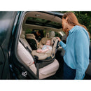 Cybex Callisto G 360° rotating all-in-one convertible car seat in beige, with a baby seated and a woman interacting.
