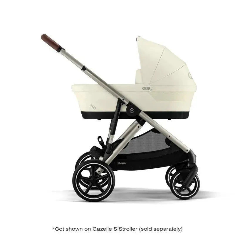 Cybex Gazelle S Cot in Seashell Beige attached to a black stroller framework, showcasing its design and functionality.