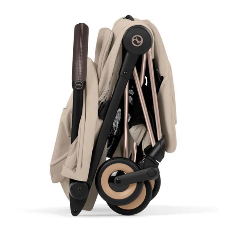 Cybex Platinum Coya Stroller in Cozy Beige with a Rose Gold frame, folded for compact storage.