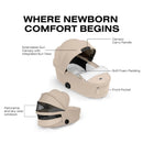 Cybex Priam Fold Lux Carry Cot in Cozy Beige with extendable sun canopy, soft foam padding, front pocket, and panoramic windows.