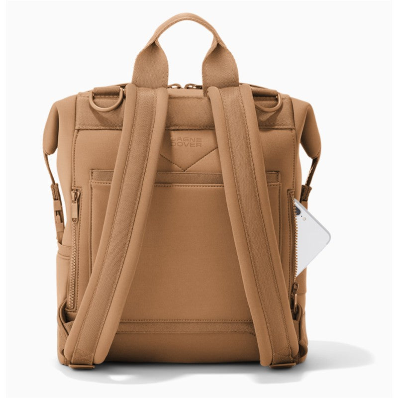 Medium Dagne Dover Indi Diaper Backpack in camel color, featuring adjustable straps and a side pocket with a phone visible.