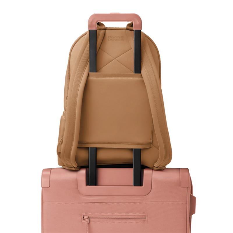 Large camel-colored Dagne Dover Dakota Backpack with black straps, positioned on a pink suitcase.