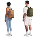 Dagne Dover Dakota Backpack in Dune, shown on a woman in blue workout attire and a man in casual white clothing.