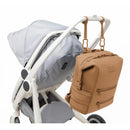 Dagne Dover Indi Diaper Backpack in camel color, attached to a stroller, showcasing its sleek design and practical storage features.