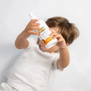 Child holding a bottle of David & Noah body wash, featuring playful graphics and an orange label, against a white background.