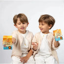 Two boys showcase the David & Noah By Baby Jolie lotion and body wash bundle, smiling and holding colorful product boxes.