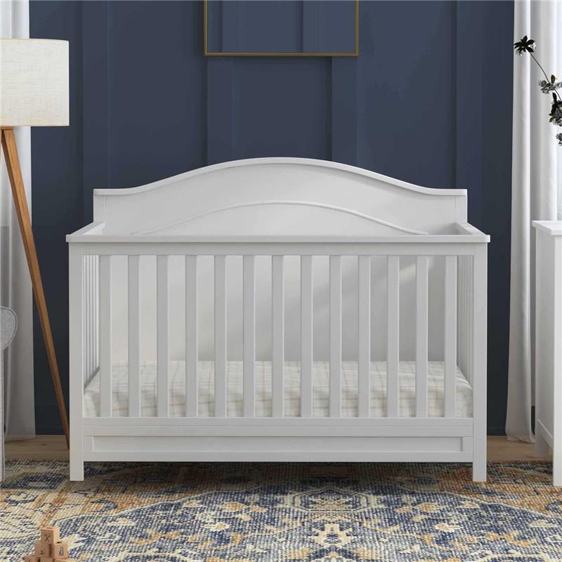 DaVinci Charlie 4-In-1 Convertible Baby Crib in white, featuring slatted sides and a curved headboard, set in a stylish nursery.