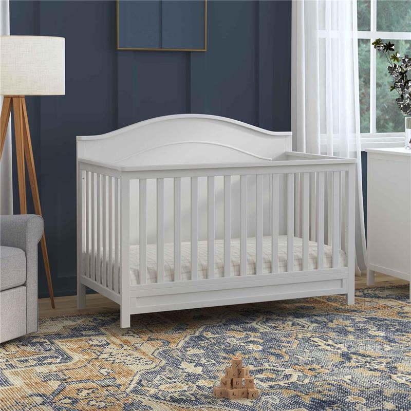DaVinci Charlie 4-In-1 Convertible Baby Crib in white, featuring a slatted design and curved headboard, set in a cozy nursery.