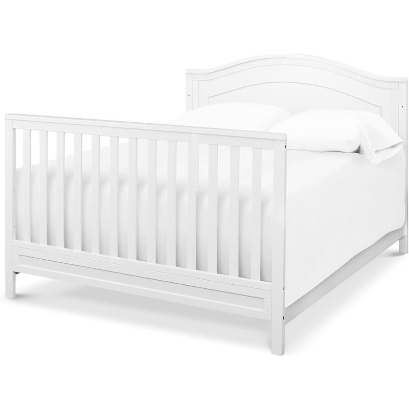 DaVinci Charlie 4-In-1 convertible baby crib in white, featuring slatted sides and a curved headboard, with a mattress and bedding.