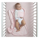 Delta babyGap TrueSleep Sleep Sack in pink, featuring a built-in swaddle, with a smiling baby lying on a dotted crib sheet.