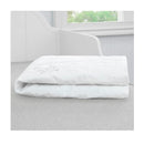 White Delta Sertapedic crib mattress liner pads folded on a gray surface, featuring waterproof and nanotex technology.