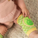 Green and yellow dinosaur knee pads on an infant, featuring a smiling dinosaur face and chevron pattern.