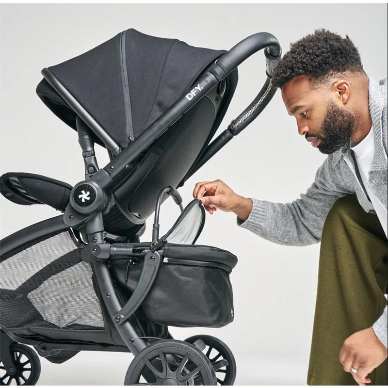 A man adjusts the canopy of a DFY - R1 Cool Box Black stroller while inspecting its mesh storage area.
