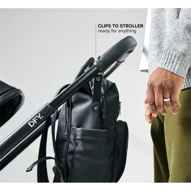 Black DFY R1 Diaper Backpack attached to a stroller, held by a person, showcasing its convenience and stylish design.