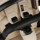 Single stroller in cream color, featuring a padded seat, adjustable harness straps, and a black handlebar.