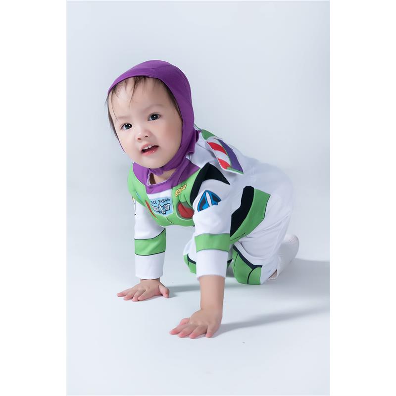 Infant wearing a Buzz Lightyear deluxe costume, crawling on a white surface with a playful expression.