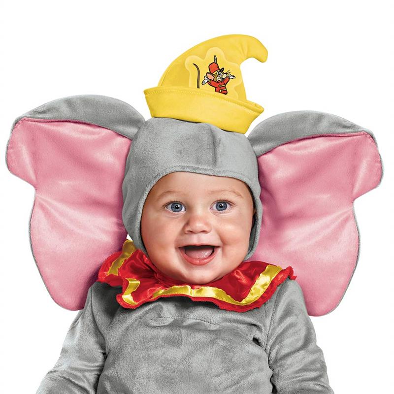 Infant wearing a gray Dumbo costume with pink ears and a yellow hat, smiling cheerfully.
