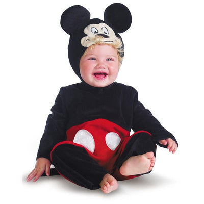 Infant wearing a black and red Mickey Mouse costume with a soft hat, smiling while sitting on the floor.