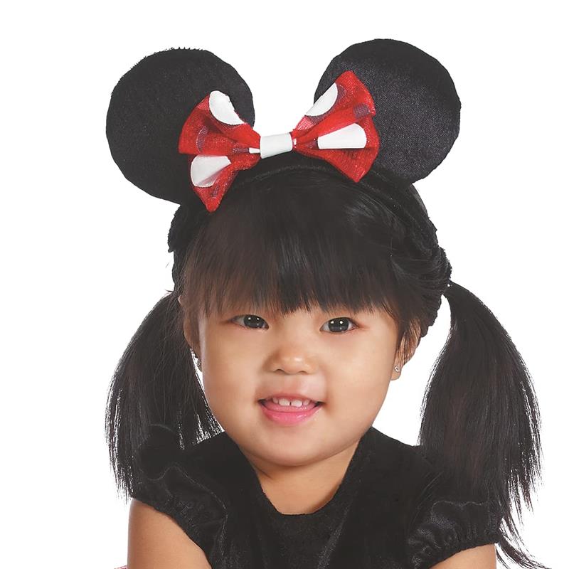 Toddler wearing a Minnie Mouse costume with black ears and a red bow, smiling against a white background.