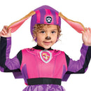 Girl wearing a purple Paw Patrol Skye costume with a hat featuring floppy ears and a paw print, smiling and posing.