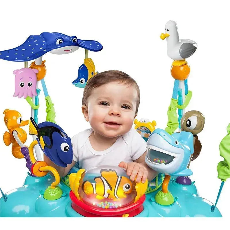 Baby smiling while seated in a colorful Disney Baby Finding Nemo jumper with various sea-themed toys.