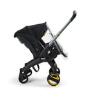 Doona rain cover on a black Doona car seat and stroller, featuring a clear front and protective design.