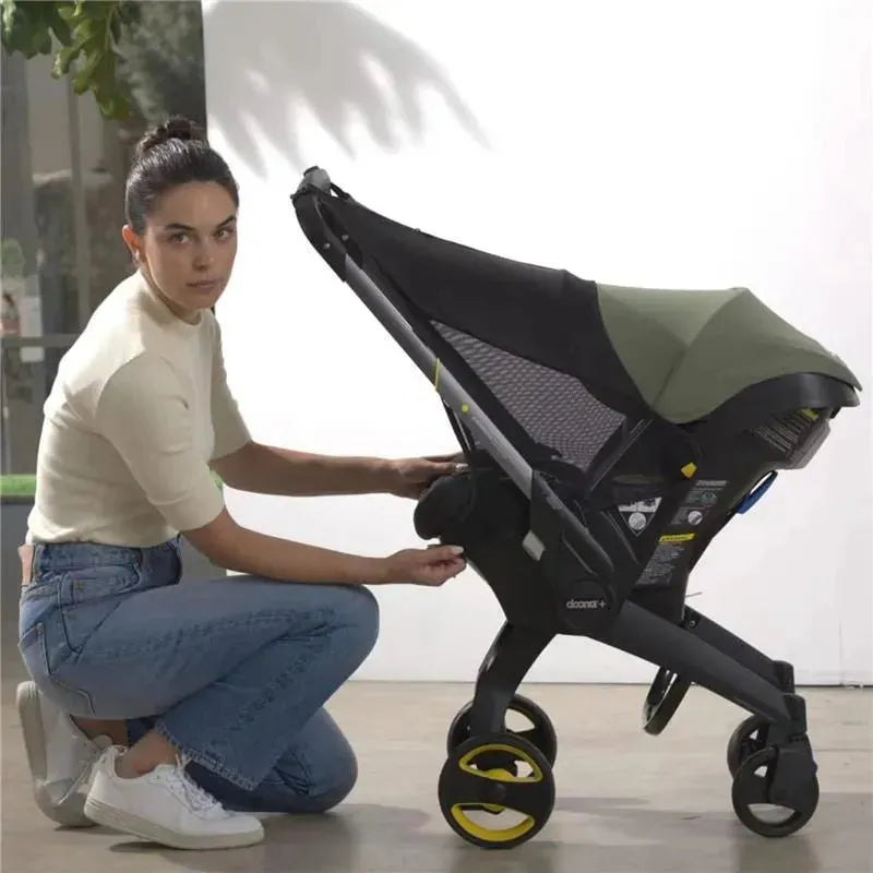 A woman adjusts the Doona Sunshade Extension on a Doona car seat and stroller, highlighting its compatibility and design.