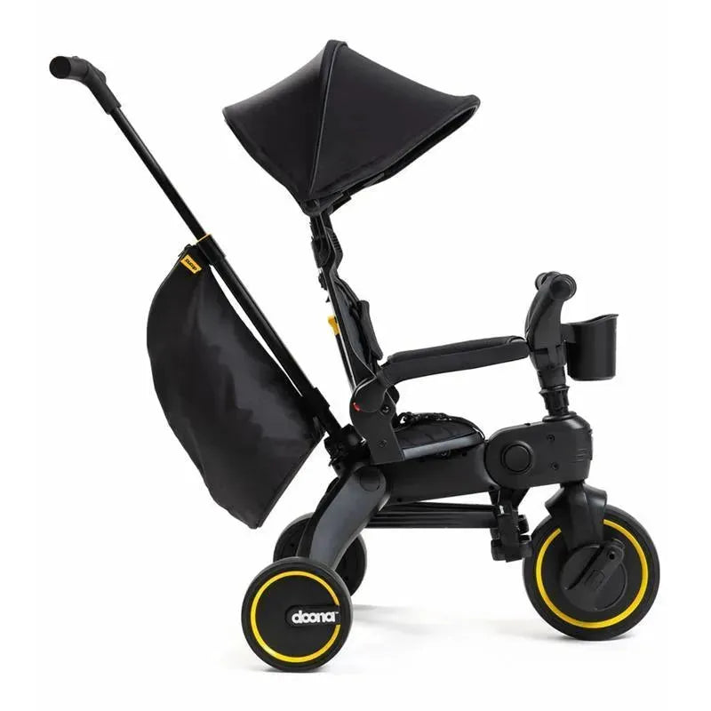 Doona Liki Trike S5 in Midnight, featuring a black frame, canopy, and yellow-accented wheels, designed for children.