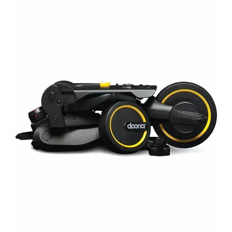 Folded Doona Liki Trike S5 in Midnight color, showcasing a compact design with black and yellow wheels and accents.