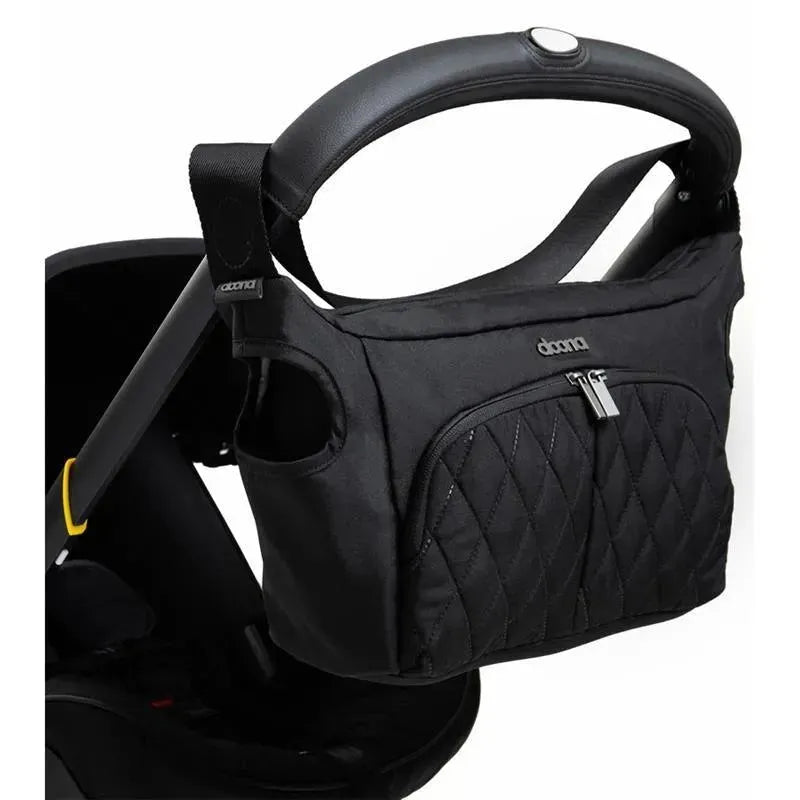 Black Doona infant car seat with a detachable storage bag, featuring a quilted design and zipper closure.