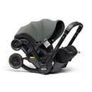 Doona X Infant Car Seat in Slate Green with a detachable Latch base and visible safety labels.