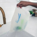 Hand holding a Dr Brown 100% silicone microwave steam sterilizer bag under a faucet, showcasing its reusable design.
