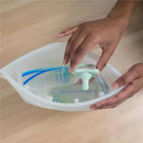 Hands holding a Dr Brown 100% silicone microwave steam sterilizer bag with a green sealing clip and measurement markings inside.