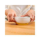 Suction bowls secured on a wooden surface, with a person placing a bowl on a yellow no-slip mat.