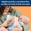 Silicone baby bottle by Dr. Brown held by a caregiver, with a baby feeding from it; features text about nipple flow.