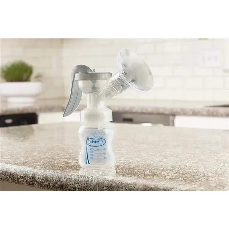 Manual breast pump by Dr. Brown with a soft silicone shield, placed on a countertop in a kitchen setting.
